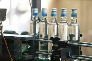 uma grandes linha do vidro garrafas em uma transportador cinto. Produção do alcoólico bebidas. foto