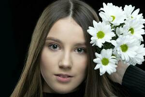 uma lindo jovem menina com natural beleza com grandes suave cabelo detém uma ramalhete do branco crisântemos. foto