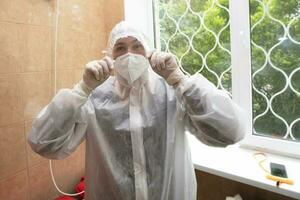 fêmea médico coloca em uma protetora médico terno e mascarar. foto