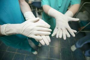 médicos vestindo borracha luvas tratar seus mãos antes cirurgia. foto