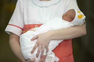 a enfermeira mãos estão segurando uma dormindo recém-nascido bebê. foto