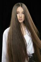 vertical retrato do uma lindo menina com muito grandes luxuoso cabelo em uma Sombrio fundo. foto
