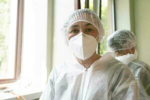 fêmea médico coloca em uma protetora médico terno e mascarar. foto