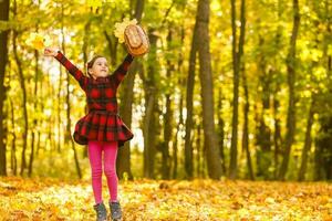 lindo pequeno menina com outono folhas ao ar livre foto