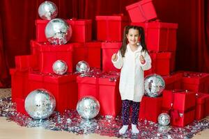 bonita pequeno menina sorridente perto vermelho Natal caixas foto