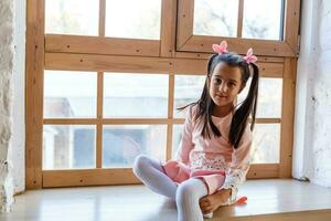 adorável criança pequena menina olhando às a janela foto