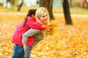 feliz família mãe e criança filha jogando e rindo em outono andar. foto