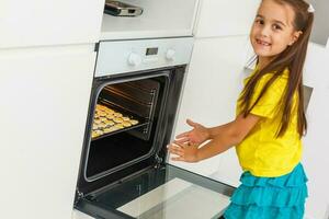 pequeno menina faz biscoitos a partir de a massa dentro a cozinha às casa foto