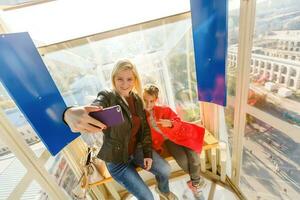 jovem mãe e filha menina levando selfie enquanto em ferris roda foto