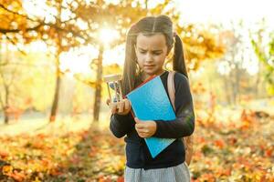 pequeno menina com ampulheta cercado de outono folhagem foto