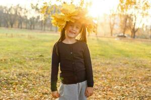 adorável pequeno menina com outono folhas dentro a beleza parque foto