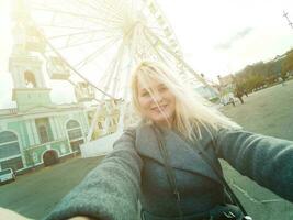 a jovem menina anda em por aí a cidade perto vistas. ferris roda. diversão parque. outono foto