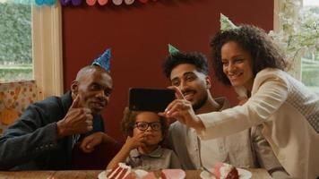 família multiétnica comemorando aniversário de menino tirando foto no telefone