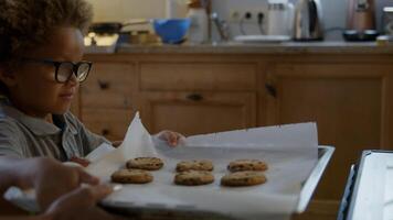 mãe e filho colocando biscoitos caseiros no forno foto