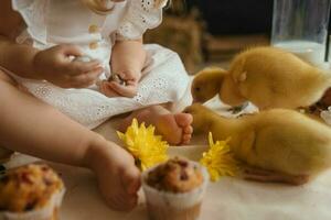 uma pequeno menina é sentado em a Páscoa mesa e jogando com fofa fofo patinhos. a conceito do a comemorar feliz Páscoa. foto