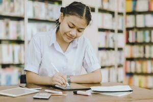 jovem escola uniforme aluna adolescente Educação Aprendendo estudando livro dentro biblioteca estante de livros fundo. foto