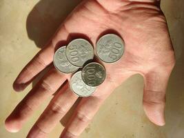 indonésio rupia moedas dentro mão com uma valor do cinco cem rupias e 1 mil rupias foto