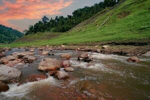 rio acima Visão em topo do a barragem cercado de montanhas e exuberante natureza foto