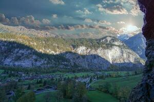 Visão do a cidade do Lauterbrunnen a partir de a rochoso penhasco perto a cascata dentro pôr do sol. foto