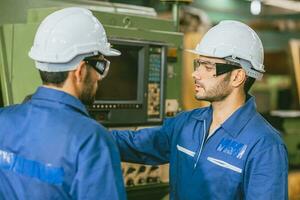 engenheiro trabalhador Treinamento equipe amigo para operar usando torno moagem cnc máquina dentro pesado metal fábrica. foto