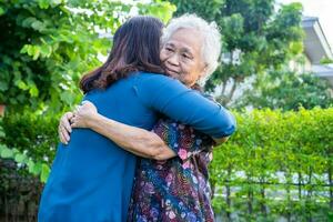 ásia idosos mulher abraço com dela filha com amor, Cuidado, ajuda, encorajar e empatia às parque, saudável Forte médico conceito. foto