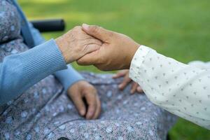 cuidador segurando mãos ásia idosos mulher paciente com amor, Cuidado, encorajar e empatia dentro parque, saudável Forte médico conceito. foto