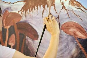 menina artista mão detém pintura escova e desenha abstrato surreal panorama em tela de pintura foto