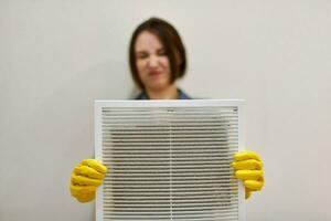 mulher segurando grade de ventilação suja e empoeirada, enojada foto