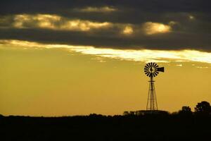 panorama com moinho de vento às pôr do sol, pampas, Patagônia, Argentina foto