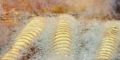 cozinhar batata frita em espiral em óleo fervente, rico em gordura e calorias fast food, delicioso e insalubre foto