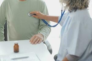 médico dando ter esperança. fechar acima tiro do jovem fêmea médico inclinado frente para sorridente idosos senhora paciente segurando dela mão dentro Palmeiras. mulher zelador dentro branco casaco apoiando encorajando velho pessoa foto