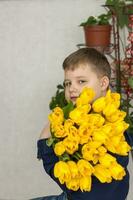 retrato do uma jovem, lindo garoto. detém uma enorme braçada do fresco amarelo tulipas. a conceito do Primavera e feriado, marcha 8, internacional mulheres dia, foto