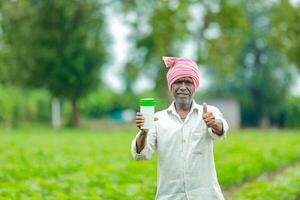 indiano feliz agricultor segurando esvaziar garrafa dentro mãos, feliz agricultor mostrando branco garrafa foto