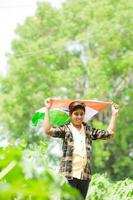 indiano Garoto segurando nacional bandeira dentro fazenda, feliz garoto, nacional bandeira foto