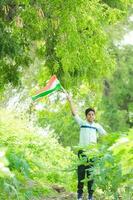 indiano Garoto segurando nacional bandeira dentro fazenda, feliz garoto, nacional bandeira foto