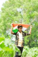 indiano Garoto segurando nacional bandeira dentro fazenda, feliz garoto, nacional bandeira foto