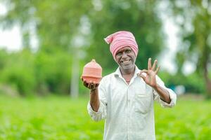 indiano agricultor segurando gullak dentro mão, salvando conceito, feliz pobre agricultor foto