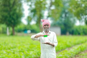 indiano feliz agricultor segurando esvaziar garrafa dentro mãos, feliz agricultor mostrando branco garrafa foto