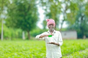 indiano feliz agricultor segurando esvaziar garrafa dentro mãos, feliz agricultor mostrando branco garrafa foto