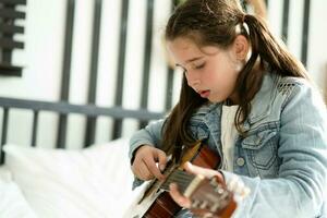 menina jogando guitarra relaxar dentro a quarto, apreciar lazer final de semana às lar. livre de estresse conceito fofa interpolação menina foto