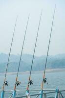 três pescaria varas dentro a rio foto