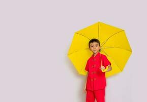 Garoto moda uma estilo chinês camisa segurando uma amarelo guarda-chuva poses para uma foto atirar.