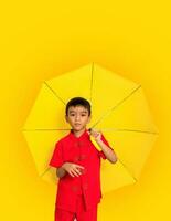 Garoto moda vestindo uma estilo chinês camisa segurando uma amarelo guarda-chuva poses para uma foto atirar.