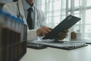médico sentado às escrivaninha e escrevendo uma prescrição para dela paciente foto