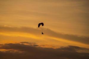 a silhueta do paramotor ao pôr do sol foto