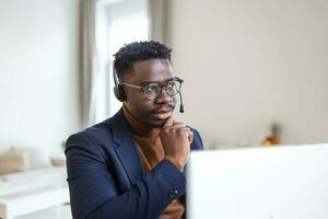 focado africano homem vestem fones de ouvido com microfone olhando às computador portátil tela escuta audio lição aprender estrangeiro língua com tutor faz vídeo chamar. aluna assistindo webinário, e estude conectados conceito foto