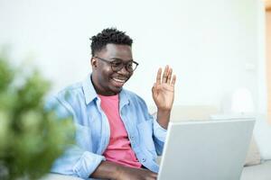 jovem e determinado Preto aluna estudando às noite às lar, com uma Socorro do uma computador portátil computador, e tendo uma Internet chamar. foto