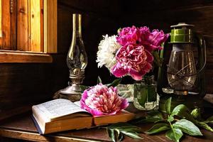 natureza morta de itens vintage e um buquê de peônias em uma mesa perto da janela em uma antiga casa de aldeia. foto