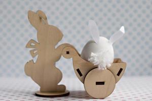um coelho de madeira carrega um carrinho com um ovo com orelhas de coelho. decorações de páscoa foto