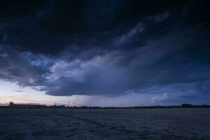 uma tormentoso céu sobre uma arenoso de praia às crepúsculo foto